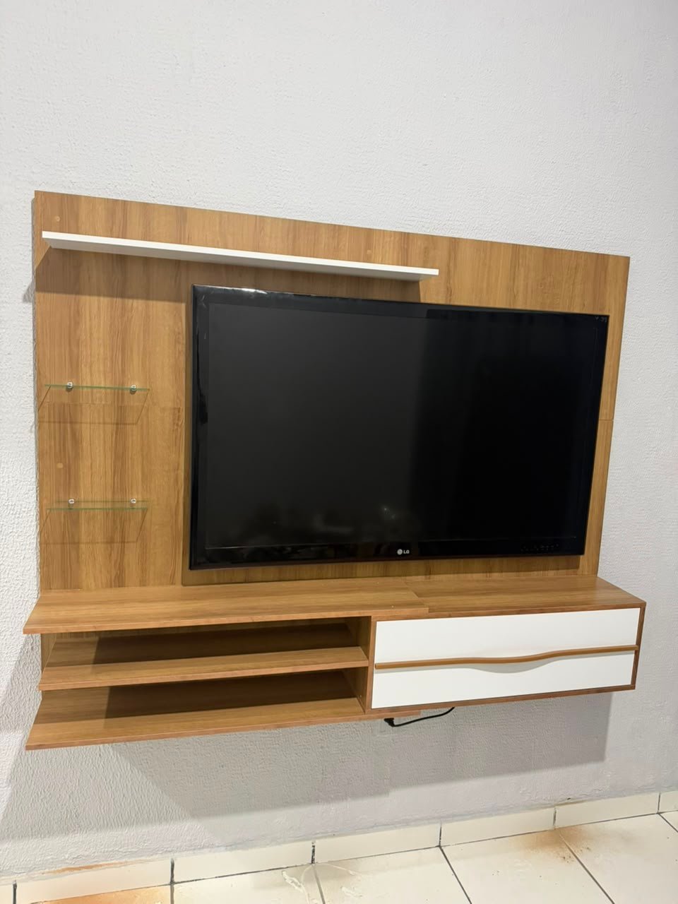 Painel de TV instalado na parede com prateleiras de vidro alinhadas